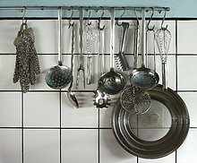 Verschiedene Küchenutensilien, die an einer Stange hängen - Stockfoto